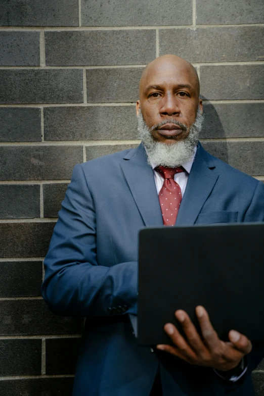 a bald man with a laptop looking at the camera