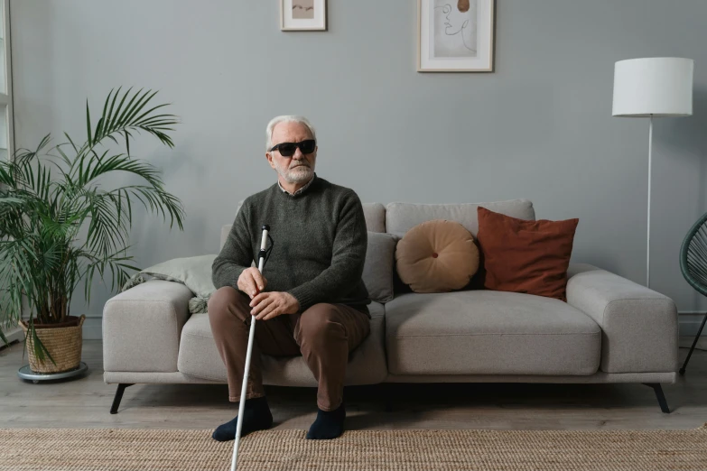 an older man is sitting on the couch with a cane