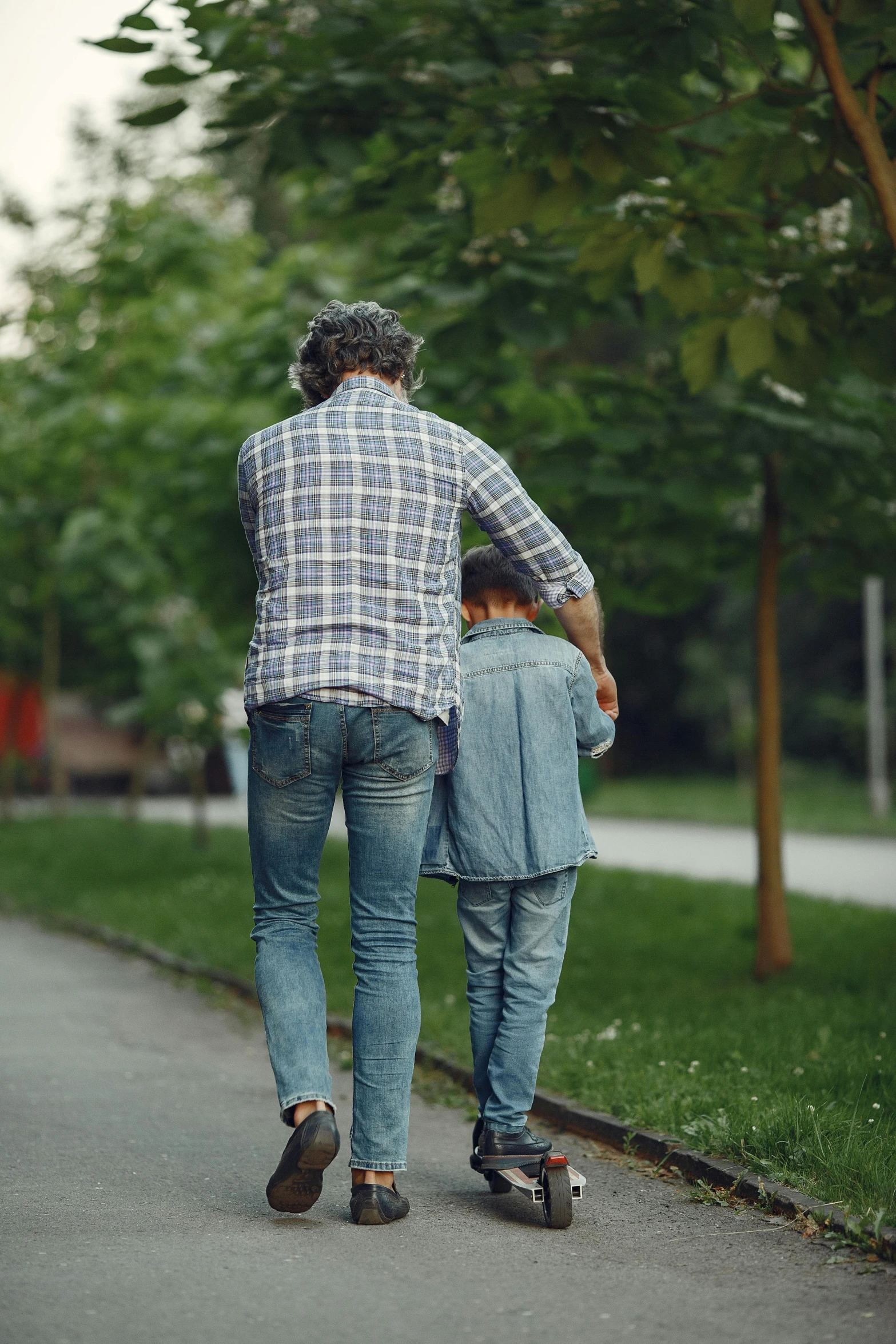 a man and child walk along a sidewalk