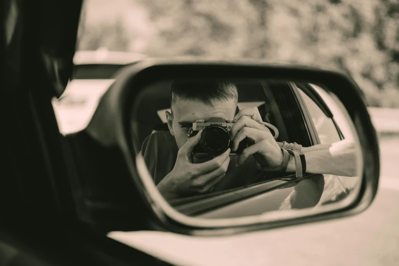 a man is taking his picture in the side mirror