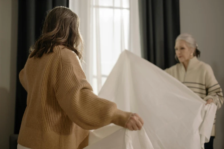 a woman opening curtains in a room with another lady