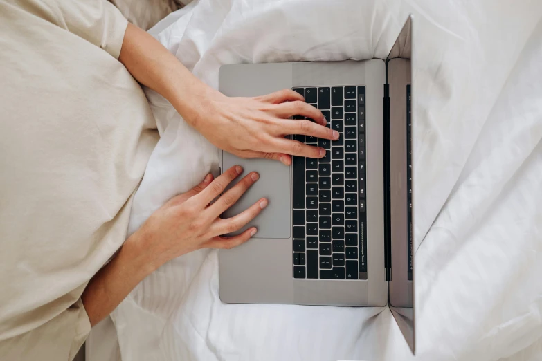 a woman using a laptop computer on her bed