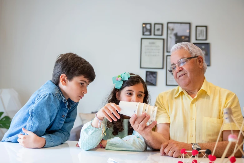 a man standing over two children sitting down at a table