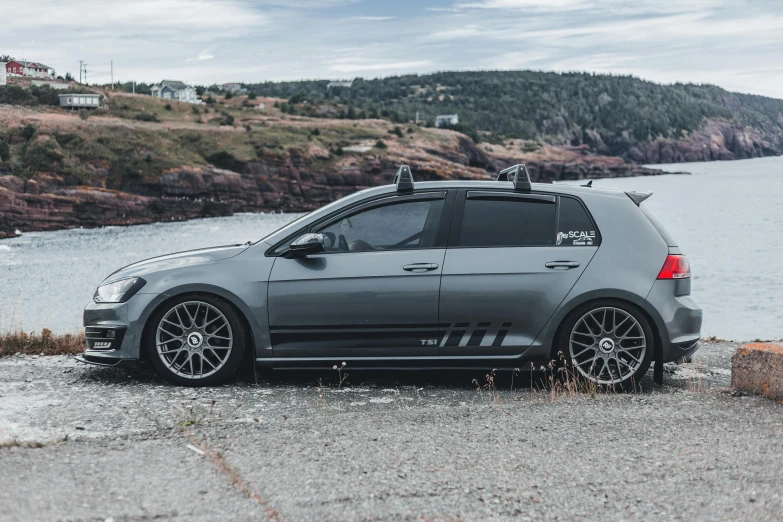 a grey car with skis strapped on top is parked near the water