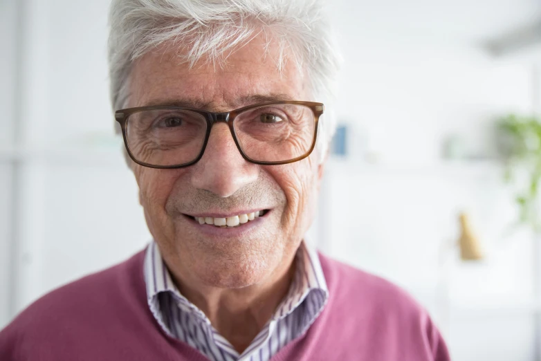 an old man with glasses smiling at the camera