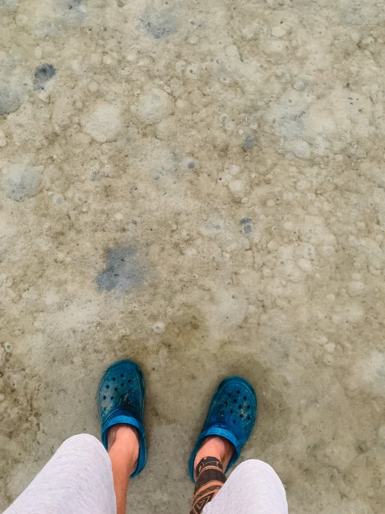 a woman wearing blue shoes looking at the ground