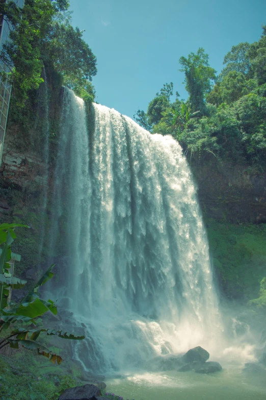 a large waterfall with lush green trees around