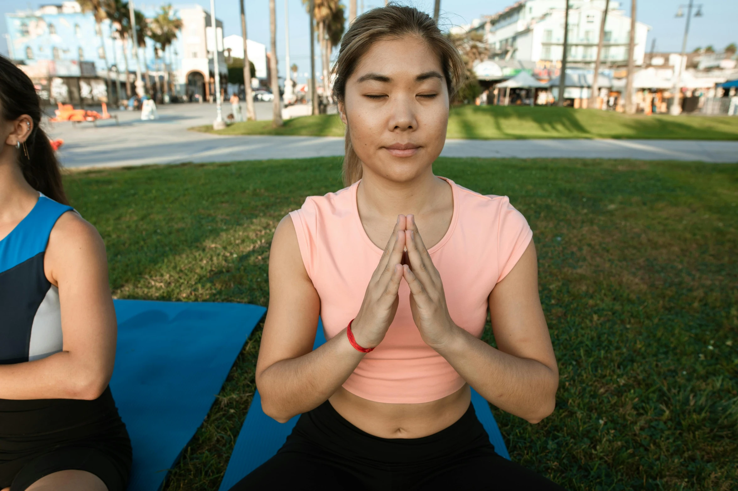 two women doing yoga outside on a blanket