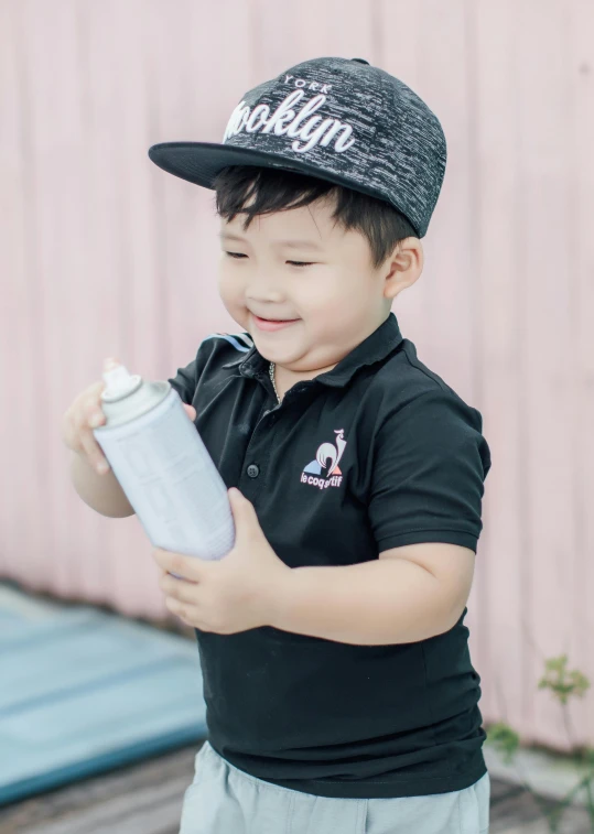 a little boy in a black shirt holding a bottle