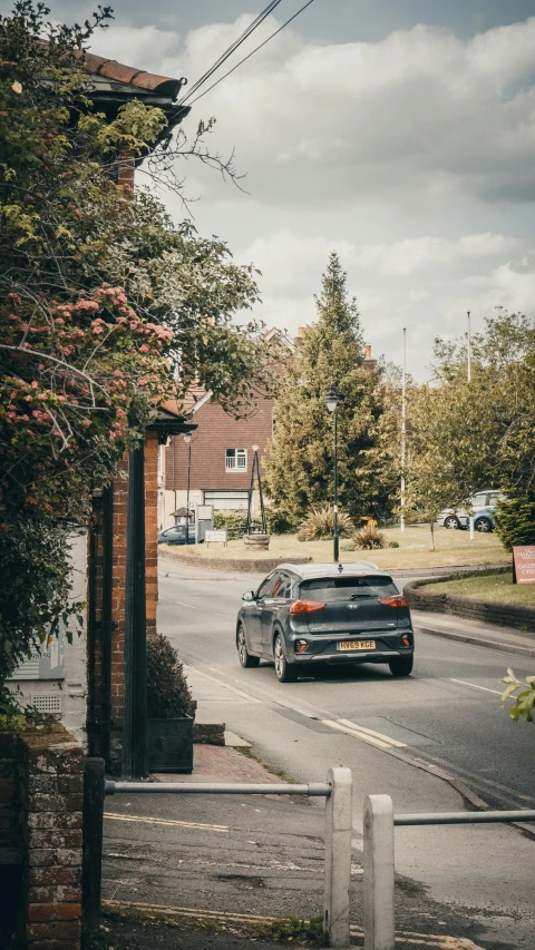 a grey car drives down a paved street