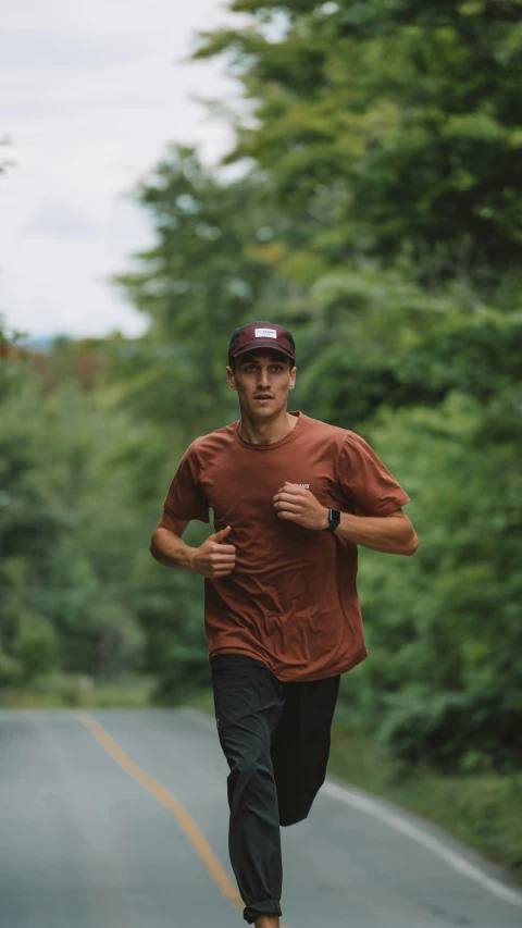 a man running down a road past tall green trees