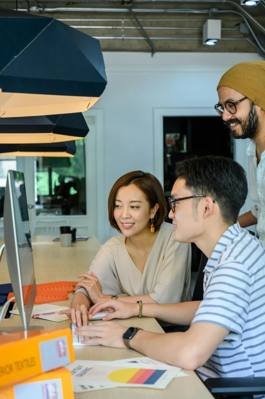 three young people looking at an open laptop computer