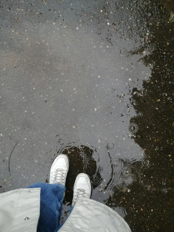 a persons legs, jeans and shoes are in the water