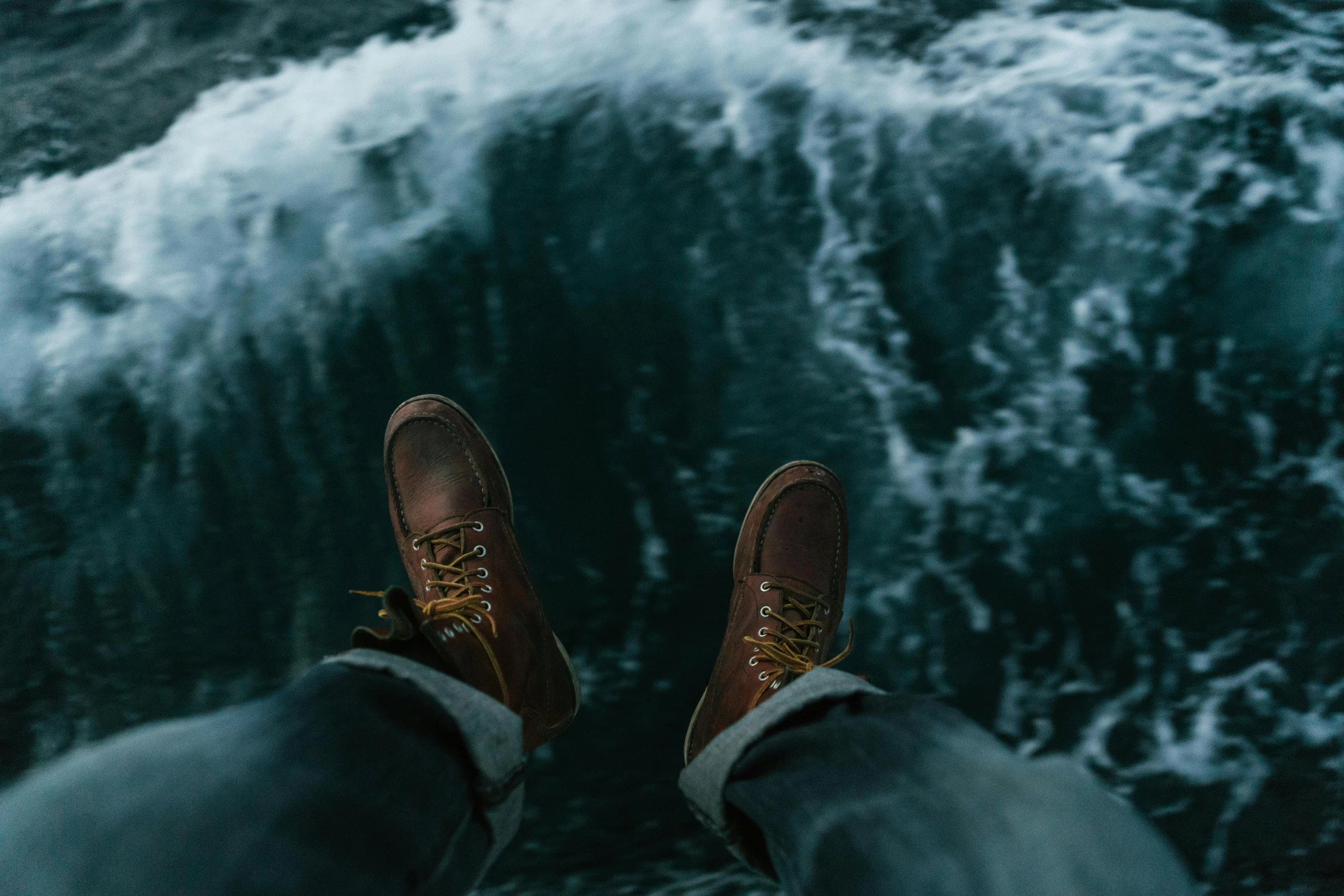 a pair of feet that are standing on the shore in front of a wave