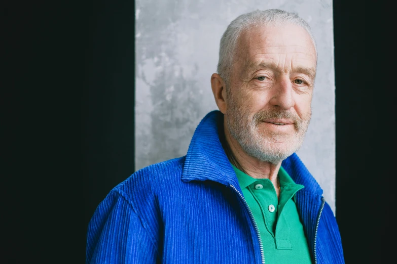 a man wearing a blue jacket in front of a black background