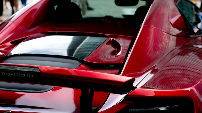 an extreme closeup of the rear windshield and front end of a red sports car