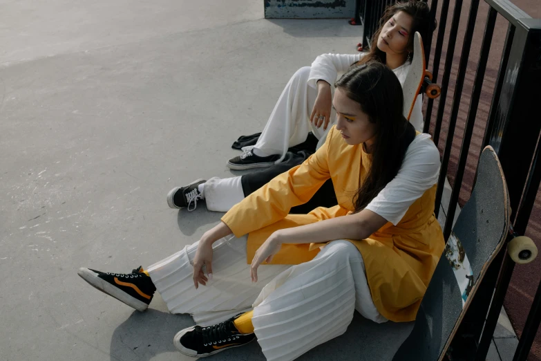 two women sitting on the ground with skateboards