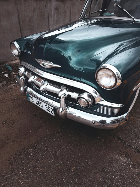 an old vintage green car parked on the pavement