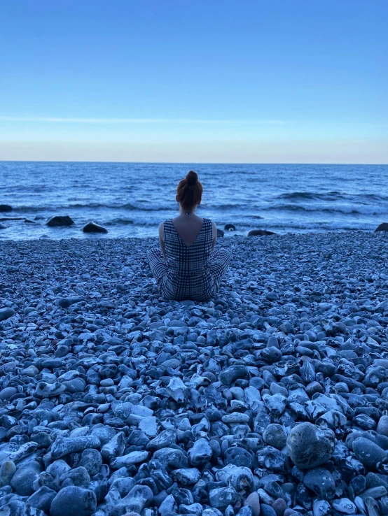 a woman is sitting on the beach in front of the ocean