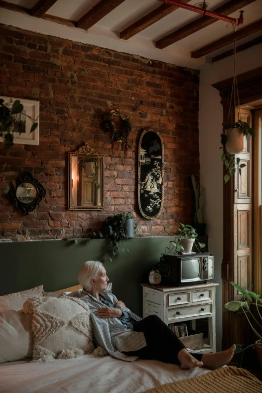 a woman sitting in a room next to a bed