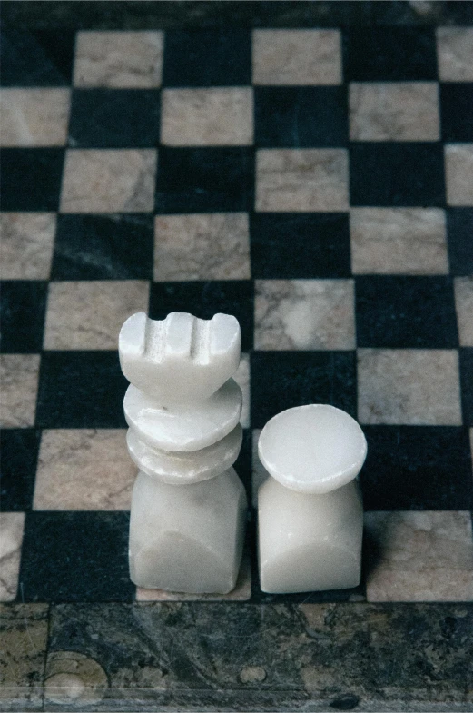 a couple of statues made out of marble blocks on a checkerboard tile floor