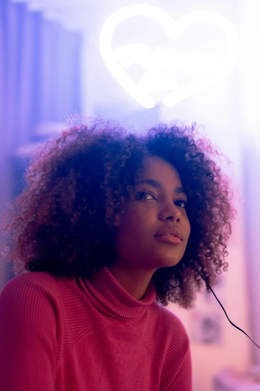 woman with curly hair, wearing a red sweater and headphones