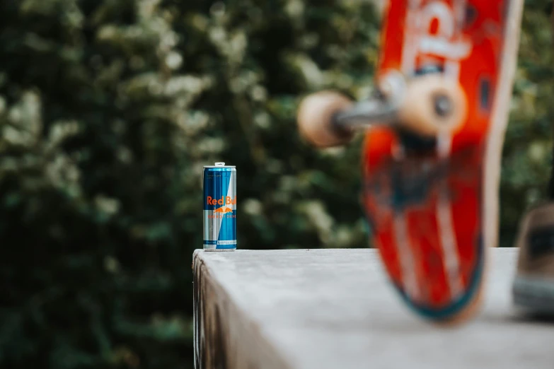 an old skateboard and an orange, orange and white can sitting on a cement ledge