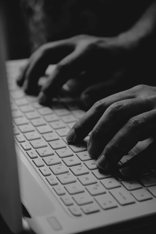 two hands typing on a keyboard on a laptop