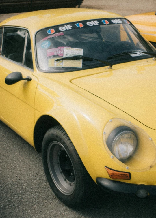 a vintage looking yellow sports car is parked in a parking lot