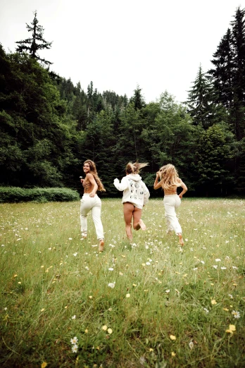 the three girls are running through the grassy field