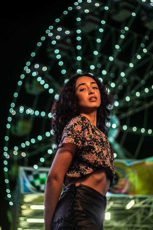 a woman standing in front of a lit up ferris wheel