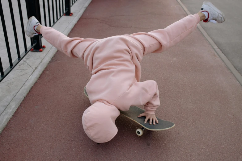 baby in pink outfit laying on feet on a skateboard