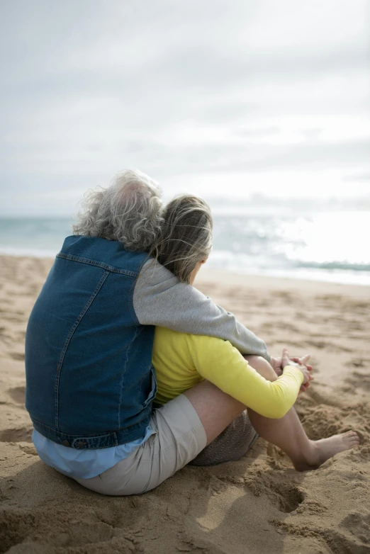 a couple sitting on top of a sandy beach