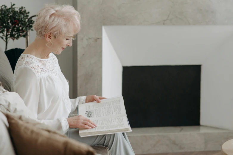 a woman sitting on a couch reading a book