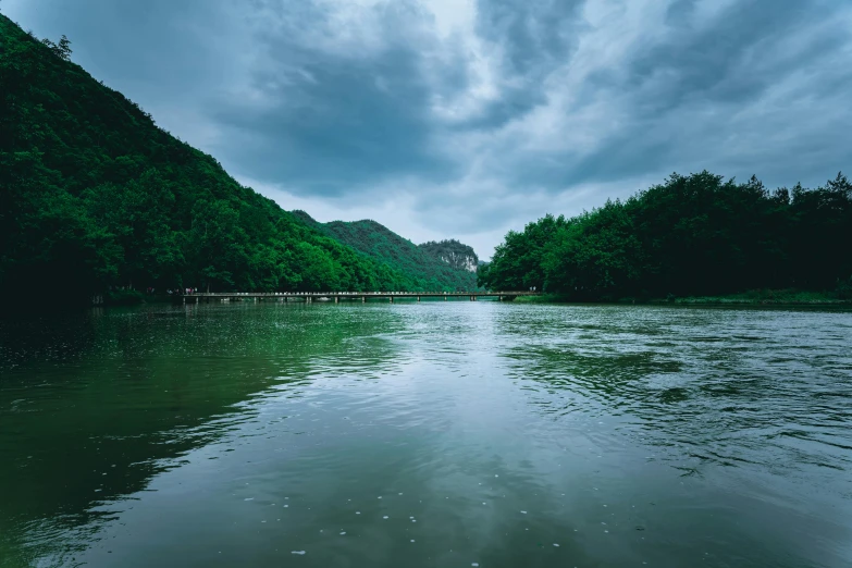 the cloudy sky is over a lake that's surrounded by mountains