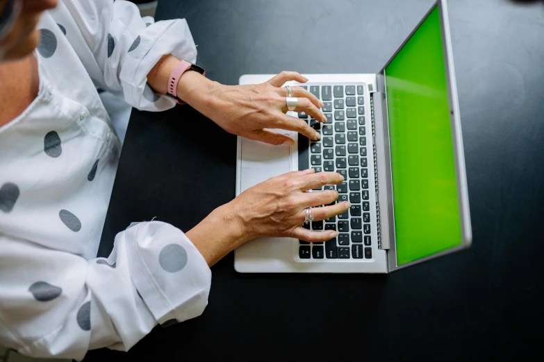 an older woman is using her laptop on the table