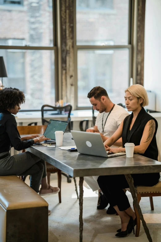 four people using their computers while sitting at a table