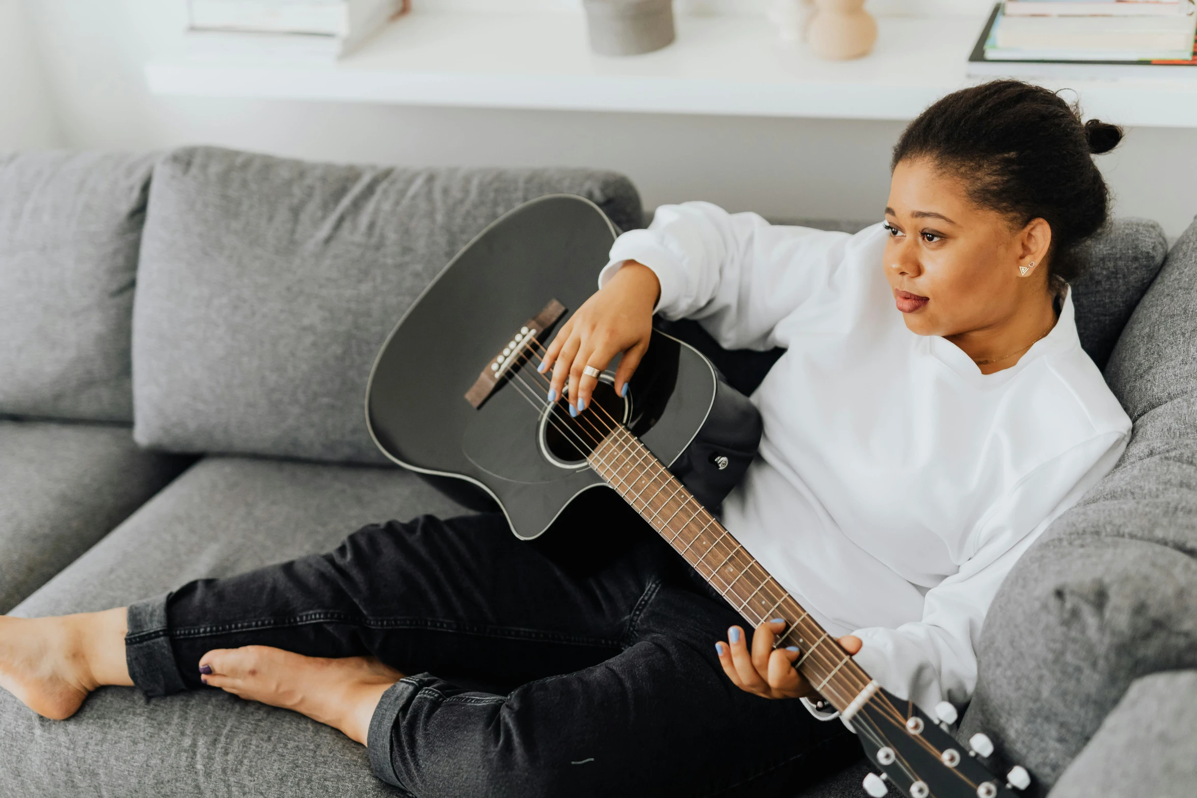 a woman sitting on a couch with an acoustic guitar in her hands