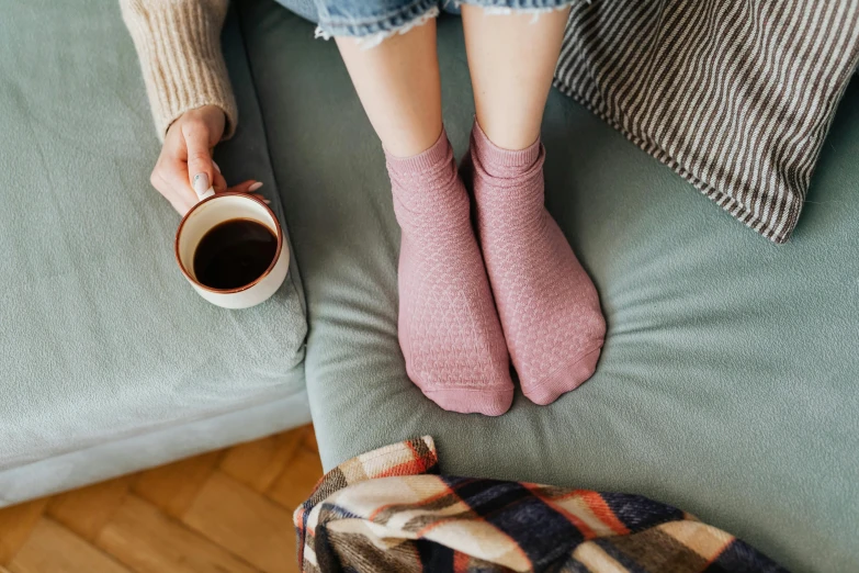 someone wearing pink slippers and holding a cup of coffee