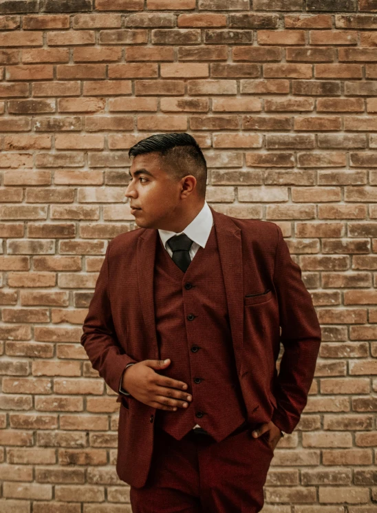 the man is posing in front of a brick wall