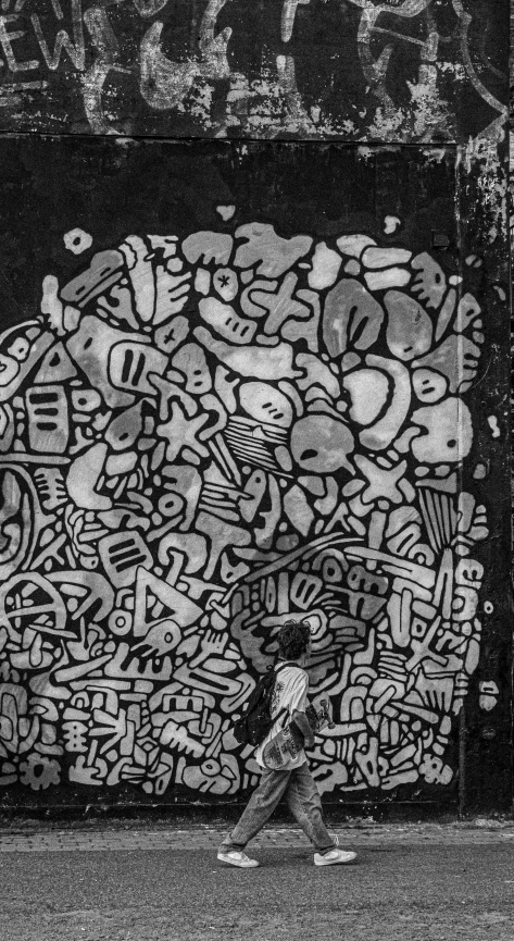 black and white pograph of someone sitting in front of a graffiti art wall