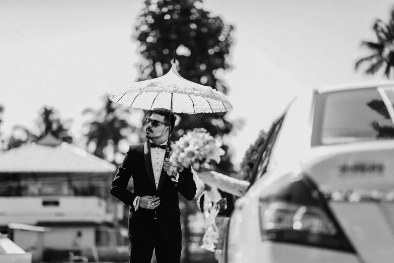 a black and white po of a man in tuxedo, holding an umbrella