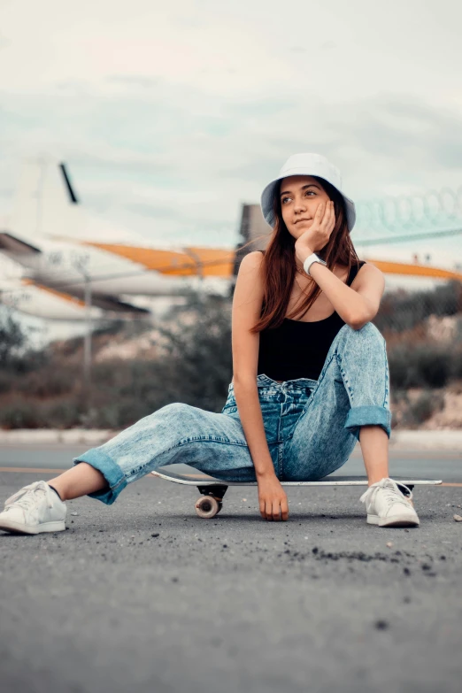 a beautiful young lady wearing a white hat leaning on a skateboard