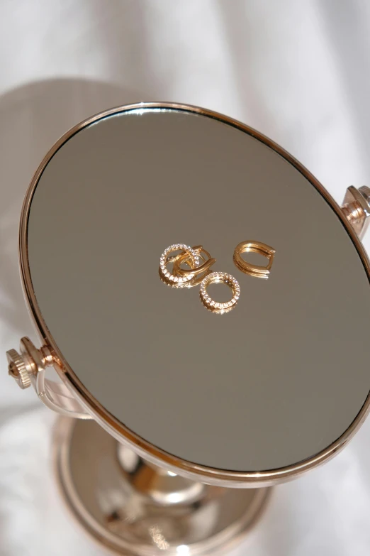 an elaborate mirror is displaying gold rings on top