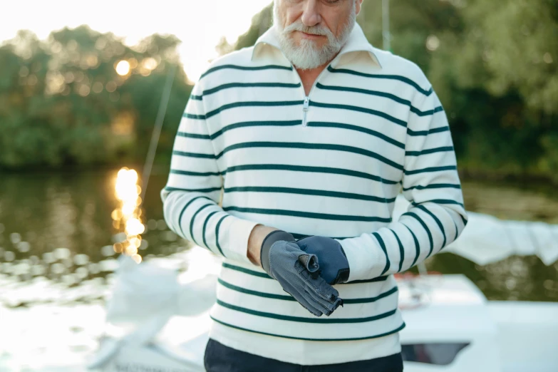 a white - haired man wears an oven mitt while standing on a boat