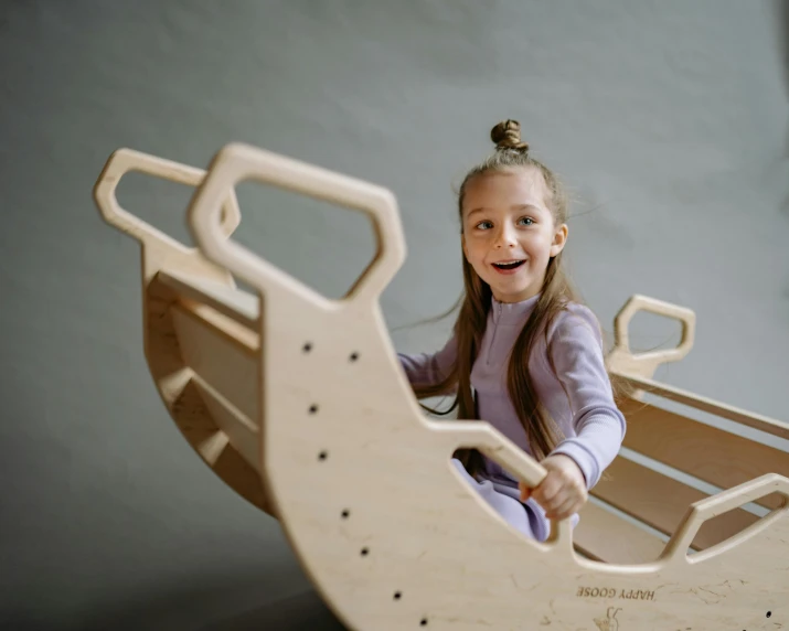 a little girl sitting on a wooden sleigh