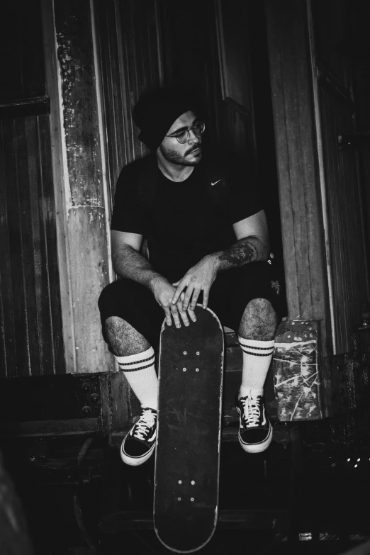 a young man sitting on a stool holding a skateboard