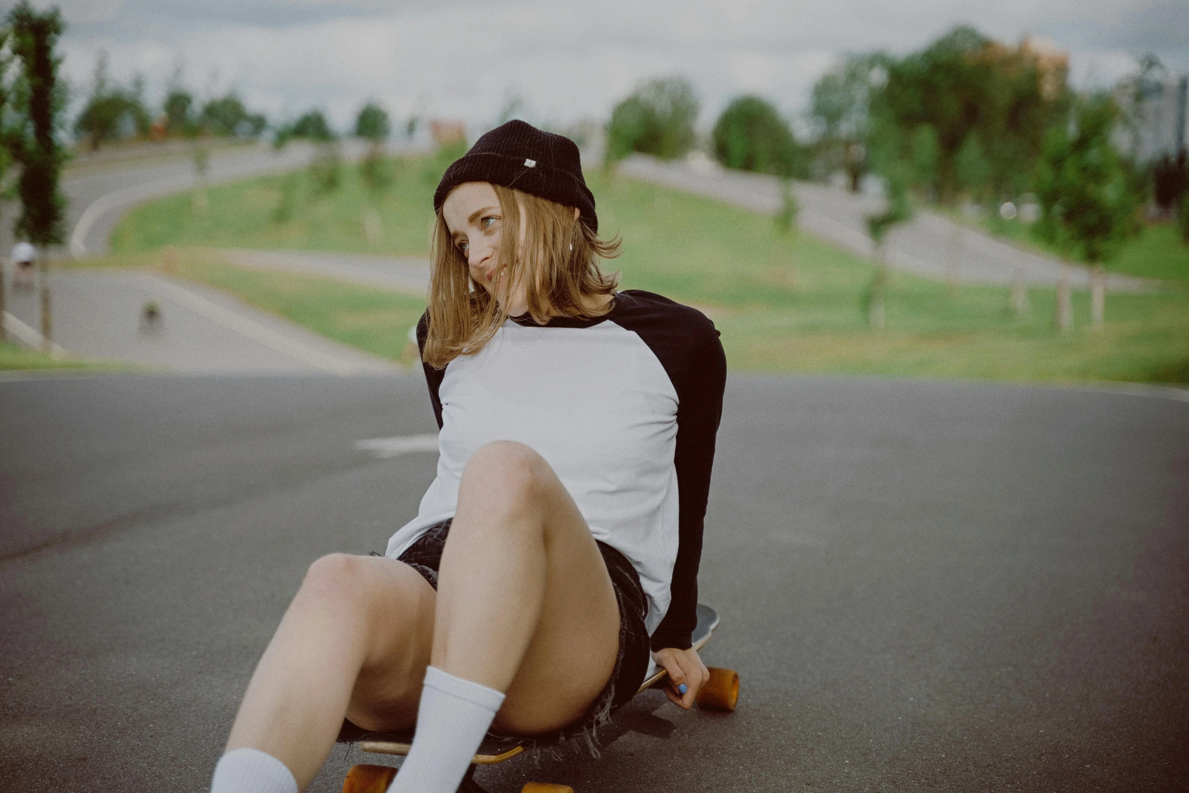 a woman sitting on her skateboard on the road