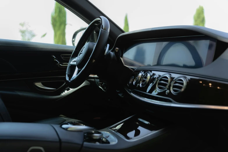 a car's steering wheel and dashboard are seen with the interior in a sleek black color