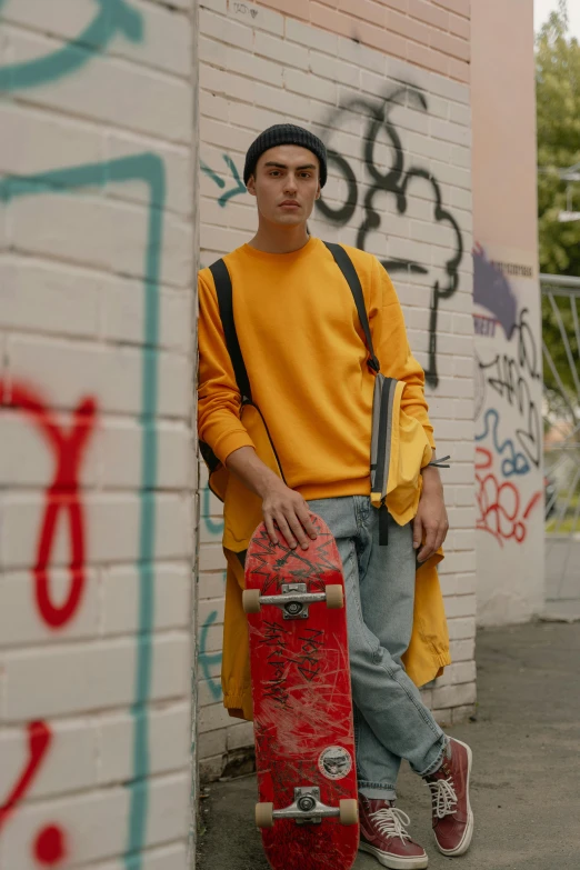 the boy is posing with his skateboard against a graffiti wall